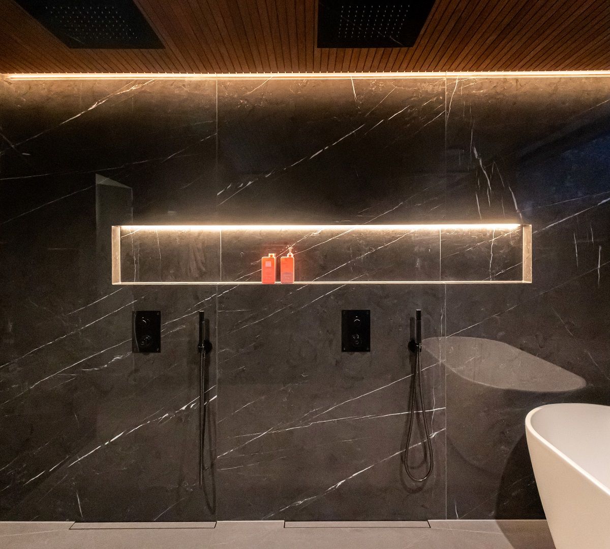 L'elemento di spicco del bagno è la mensola illuminata per shampoo con una striscia LED incassata in profilo di alluminio sulla parte superiore della mensola